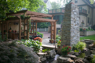 A lush backyard with a stream and pergola