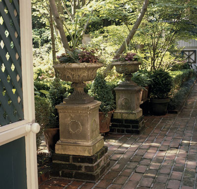 Flower pots on top of pedistals on a brick walk way