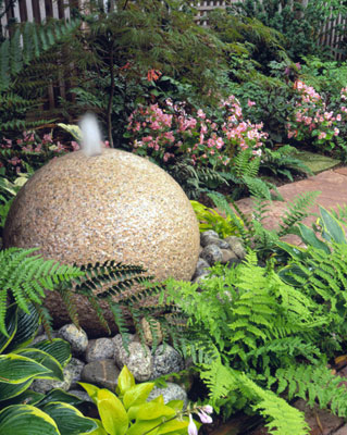 A rock fountain at the end of a brick pathway