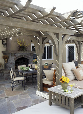 Outdoor furniture under a pergola with a built-in fireplace