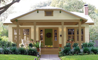 Exterior view of a house with tan siding and brown trim surrounded by plants