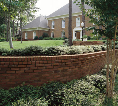 A brick and mortar retaining wall surrounded by plants