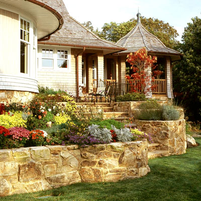 Flower beds in a retaining wall with stairs leading to the back door of a house