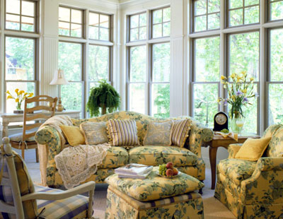 A sun room with couches and chairs in a floral pattern